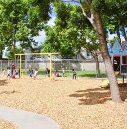 Children playing on a playground with swings and a playhouse