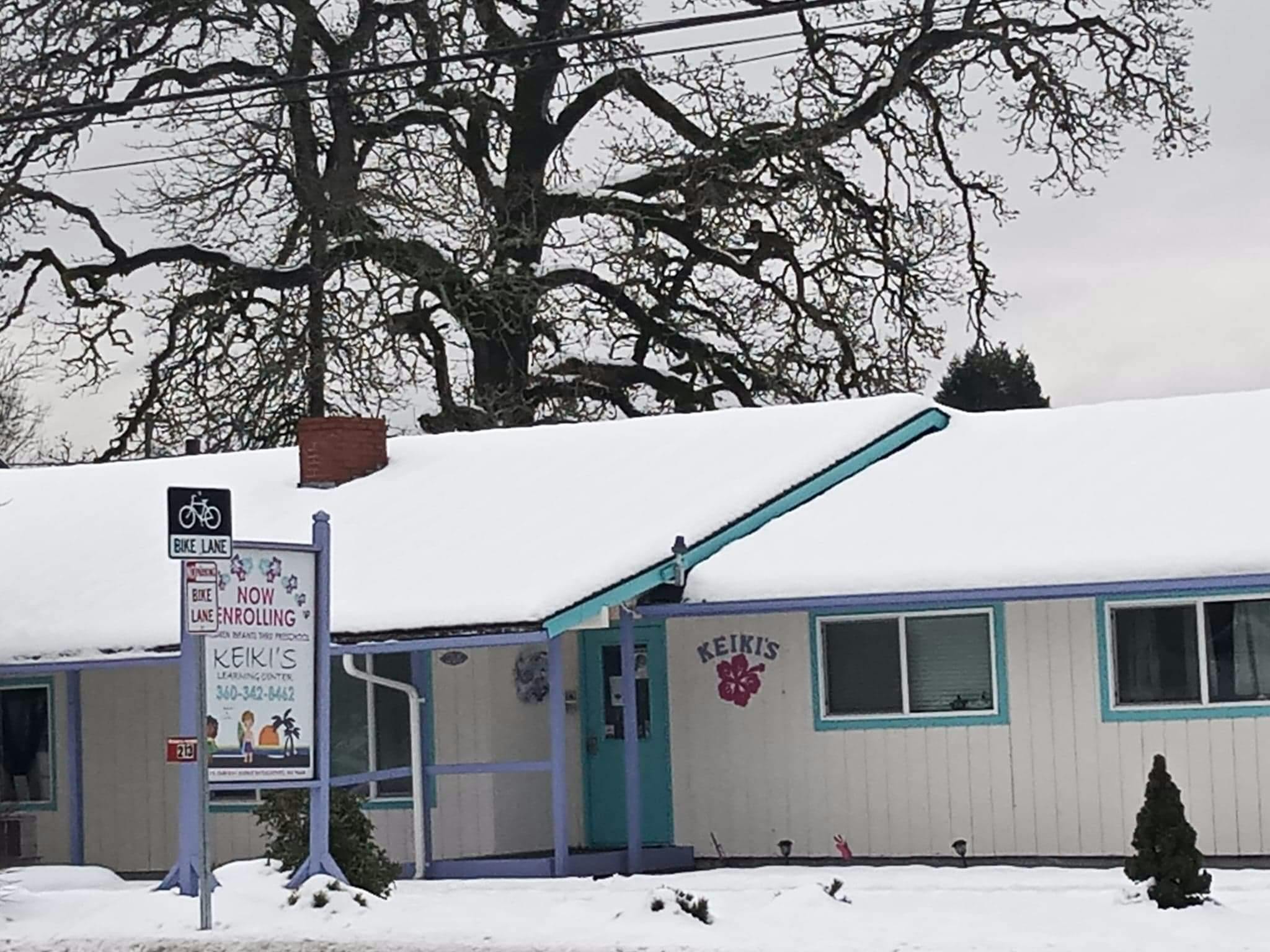 Building with a snow-covered roof and a sign in front