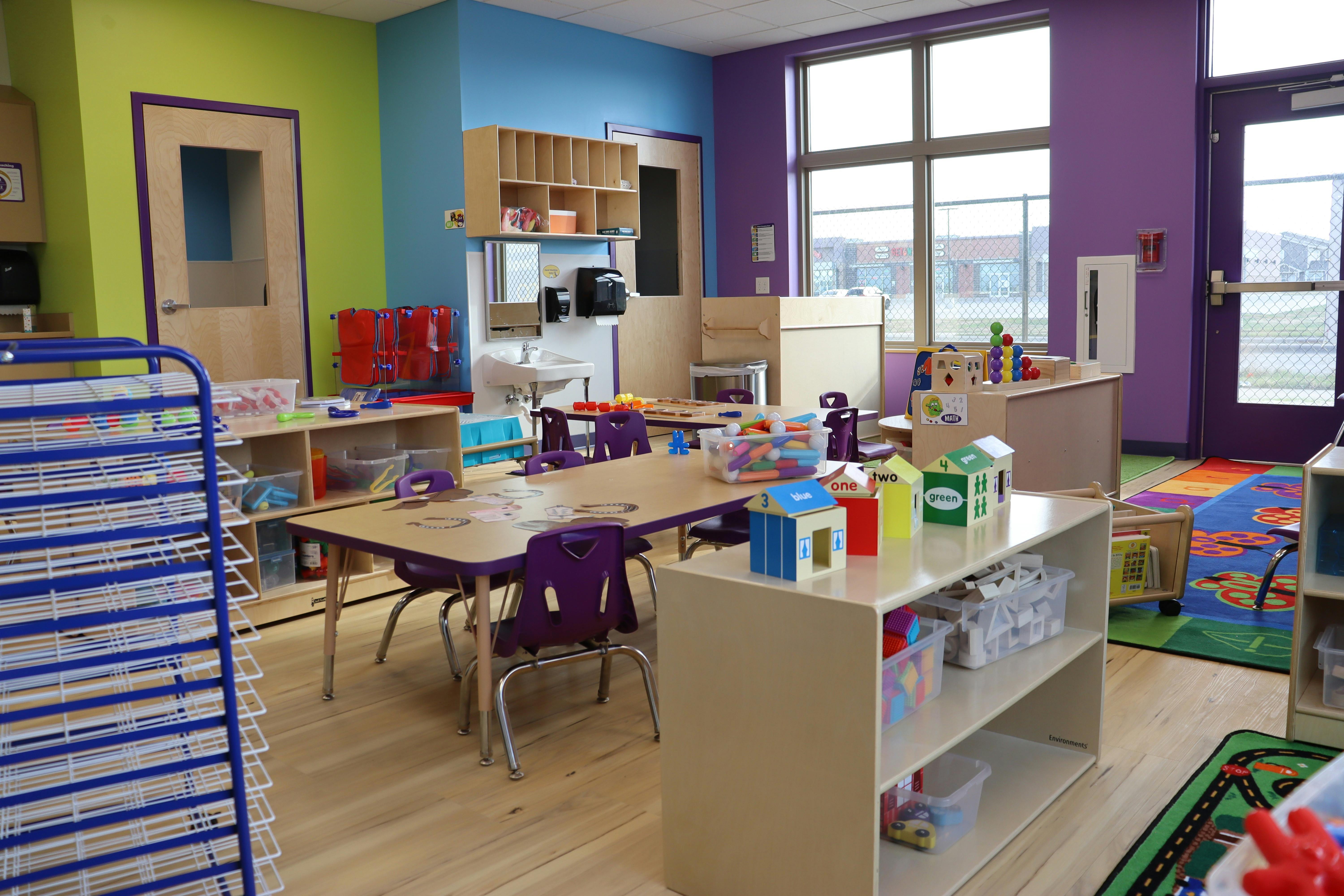 An empty early childhood classroom with colorful walls, tables, and toys