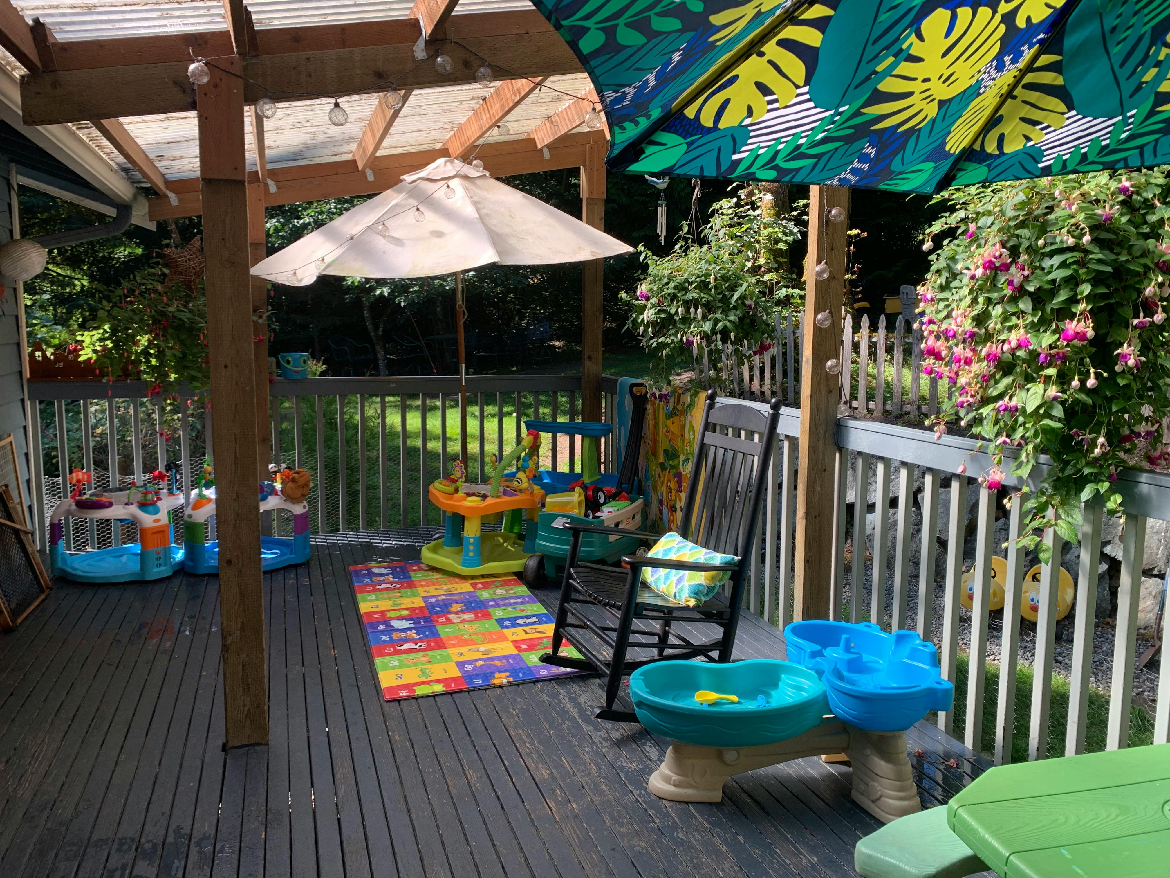 Outdoor deck with patio furniture, children's toys, and umbrellas