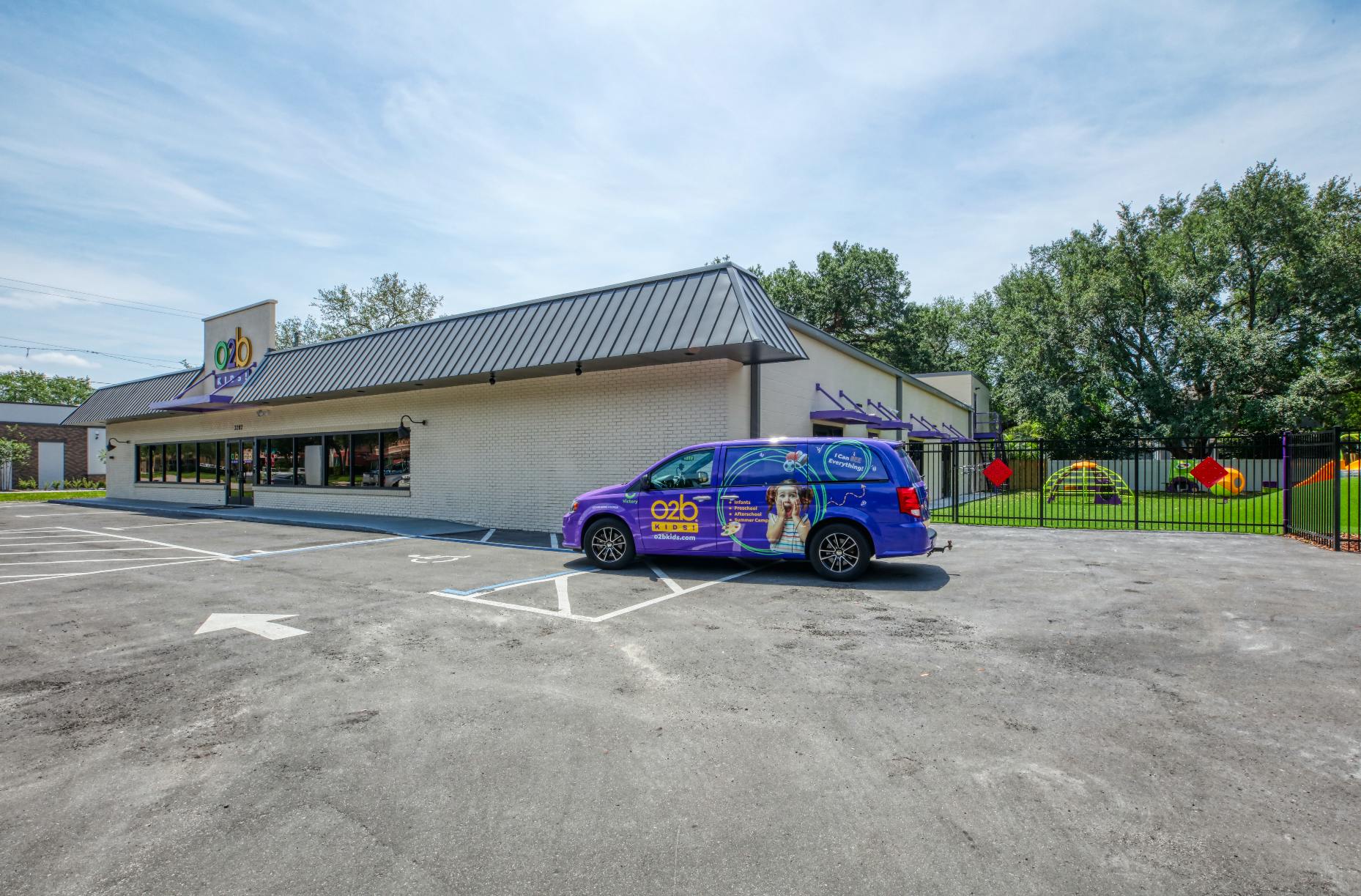 purple van parked in front of a white building with a playground