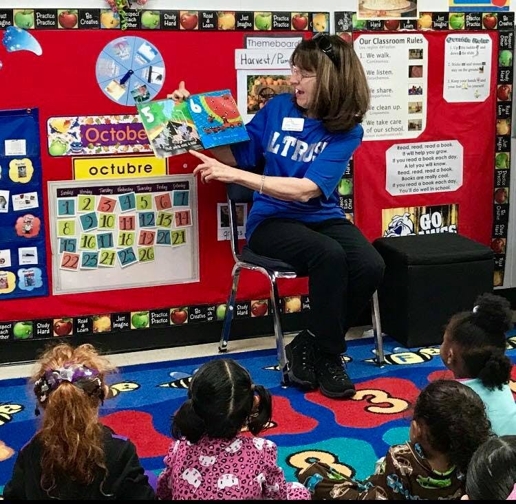 Person reading a book to children in a classroom