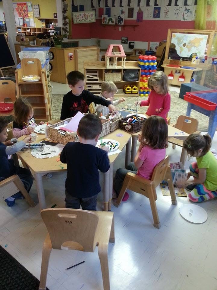 Children sitting at tables and on the floor in a classroom