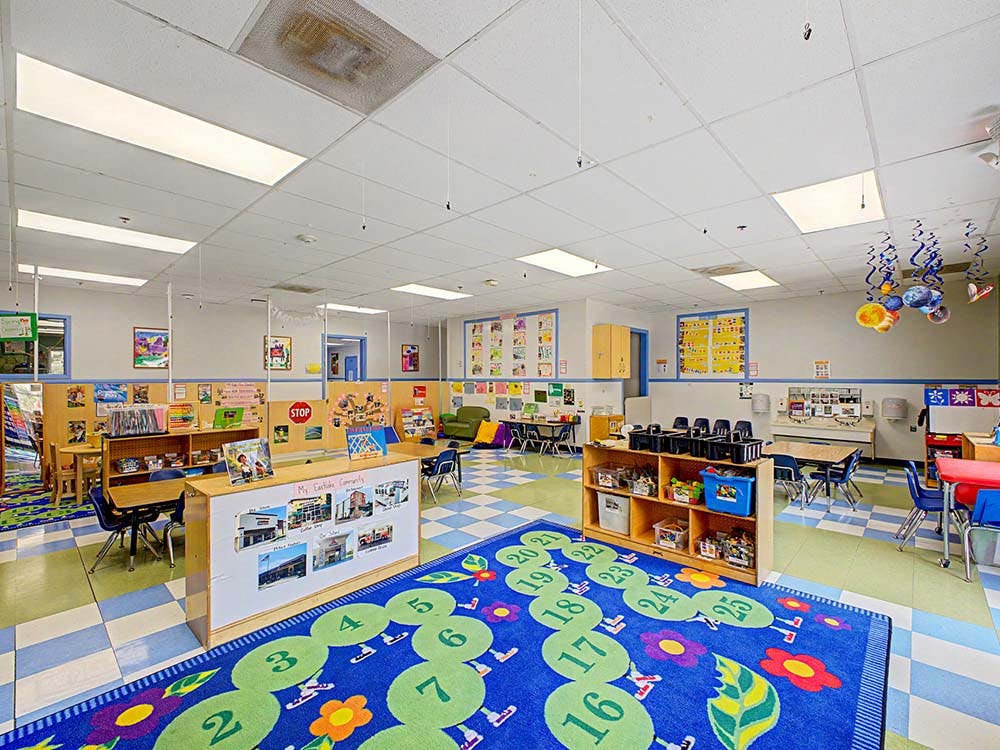 Colorful preschool classroom with tables, chairs, and play areas