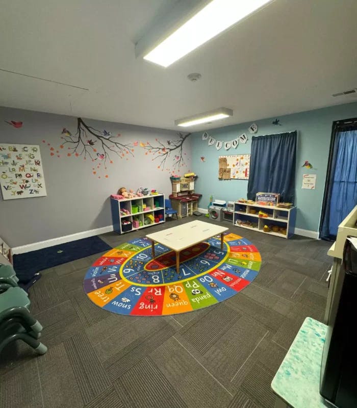 Classroom with colorful rug, small table, and shelves