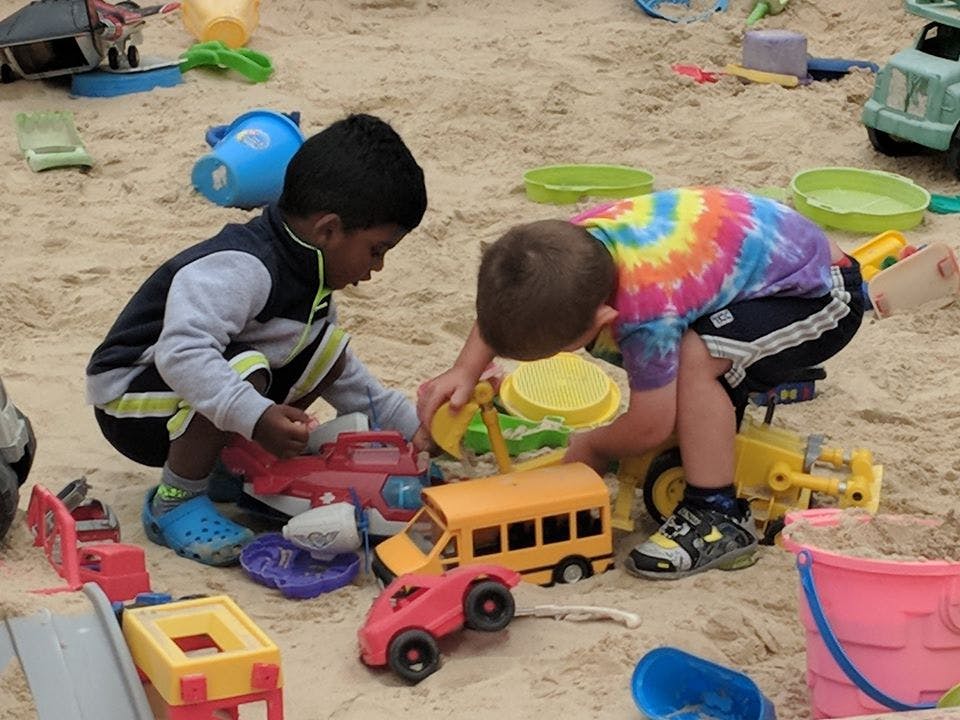Two children playing with toys in a sandbox