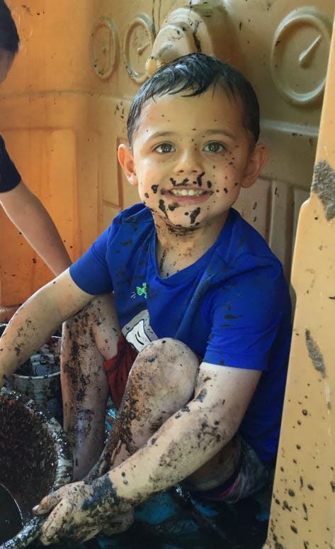 Child covered in mud, smiling