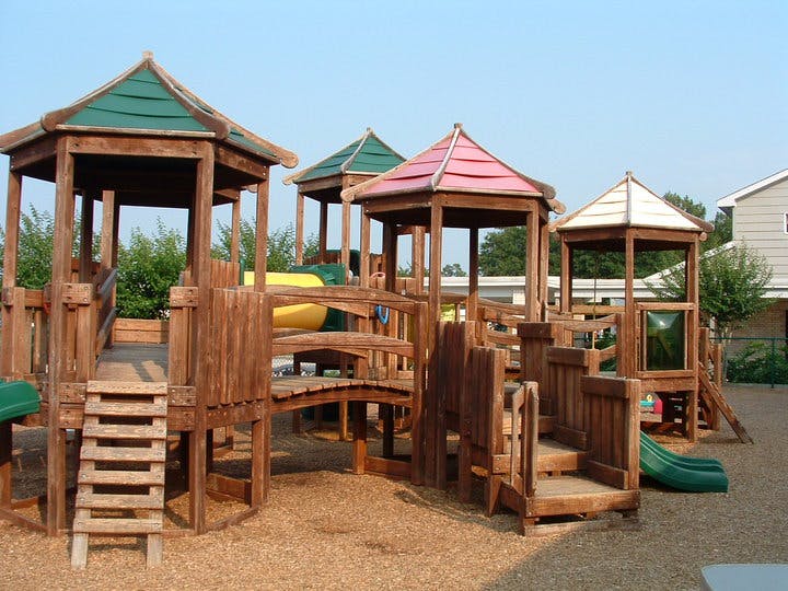 Wooden playground structure with multiple towers and slides
