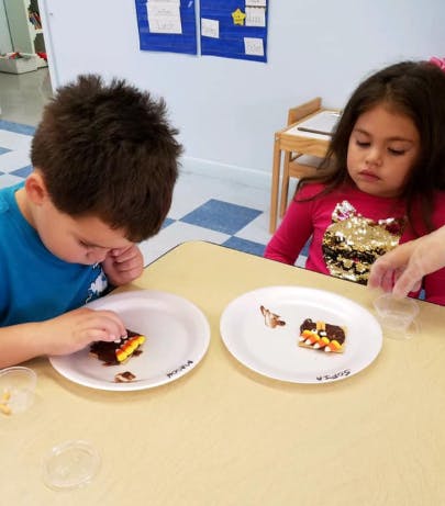 Two children decorating treats on plates at a table
