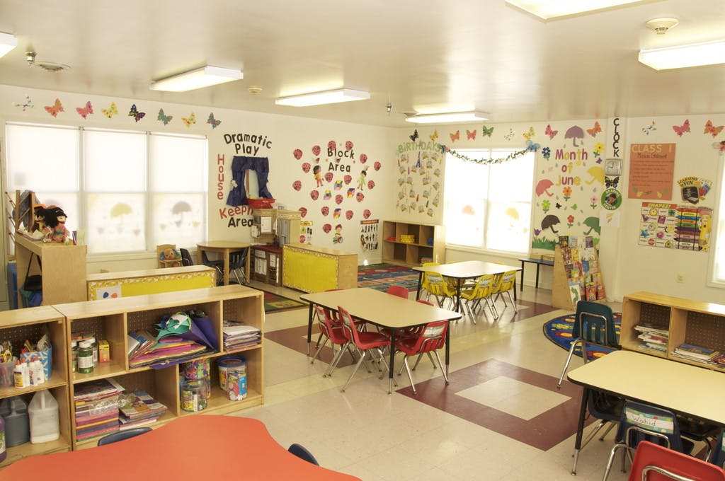 Empty classroom with small tables and chairs, decorated walls