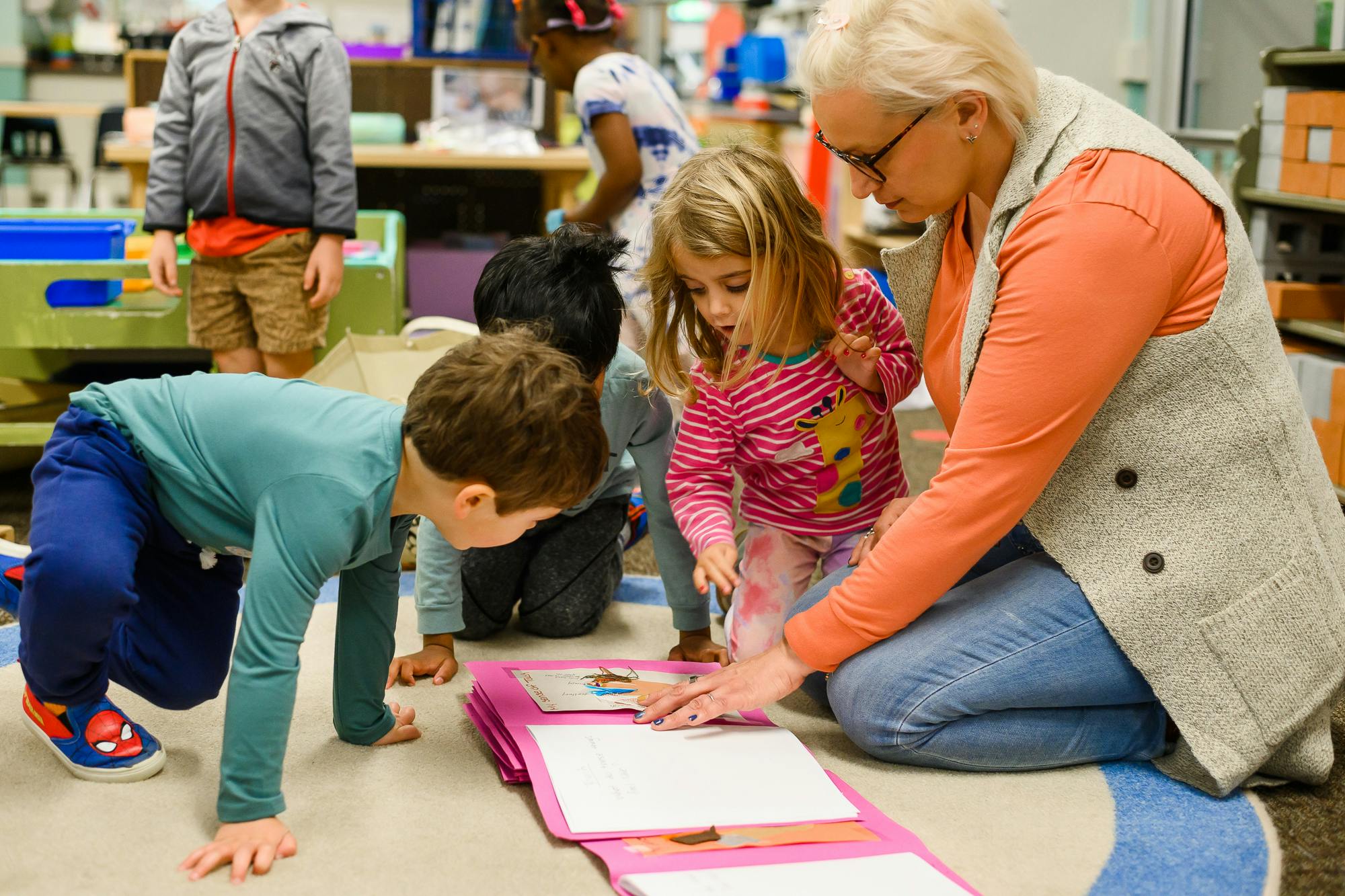 Adult and children on floor looking at a book
