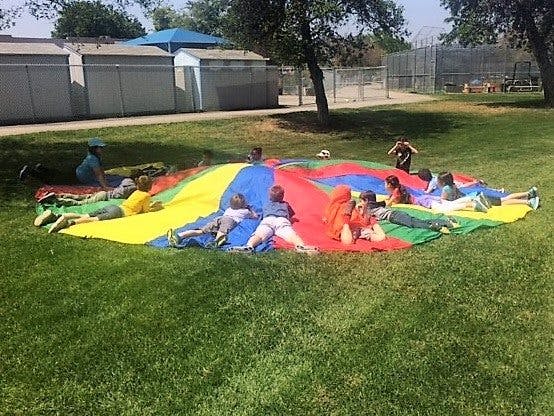 Children playing with a colorful parachute on grass