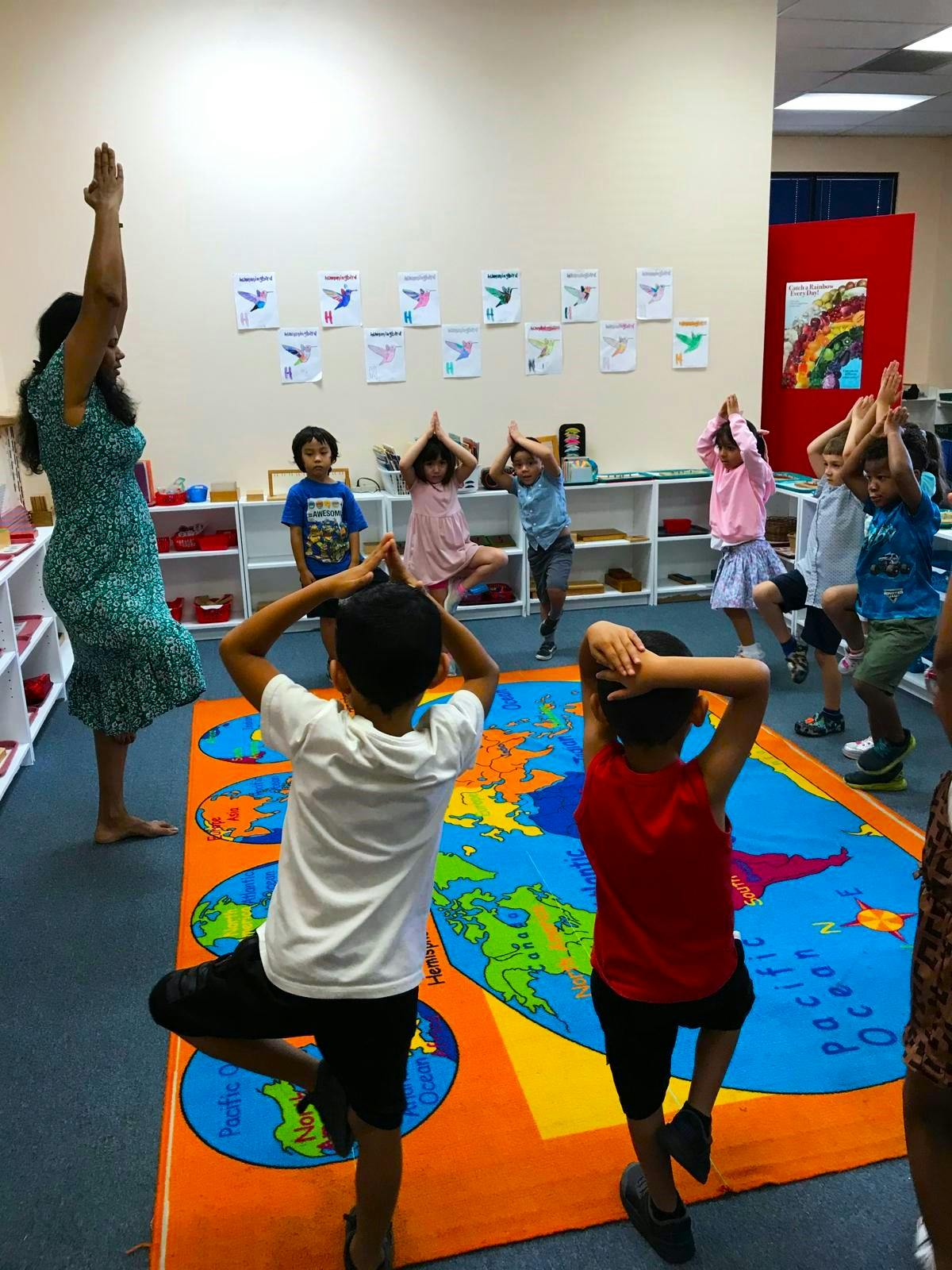 Adult and children doing yoga poses in a classroom