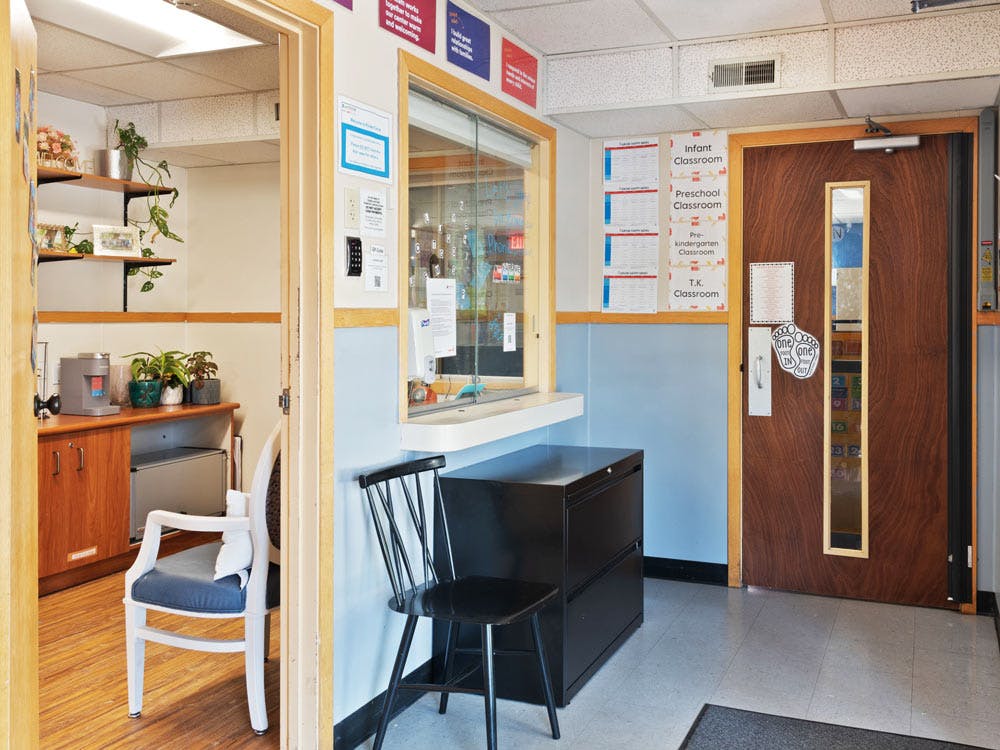 Reception area of a preschool with a wooden door and classroom signs
