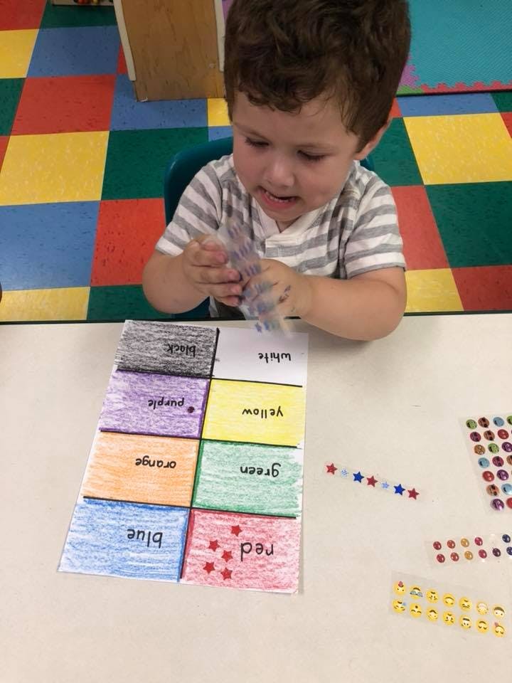 Child playing with stickers and a color chart