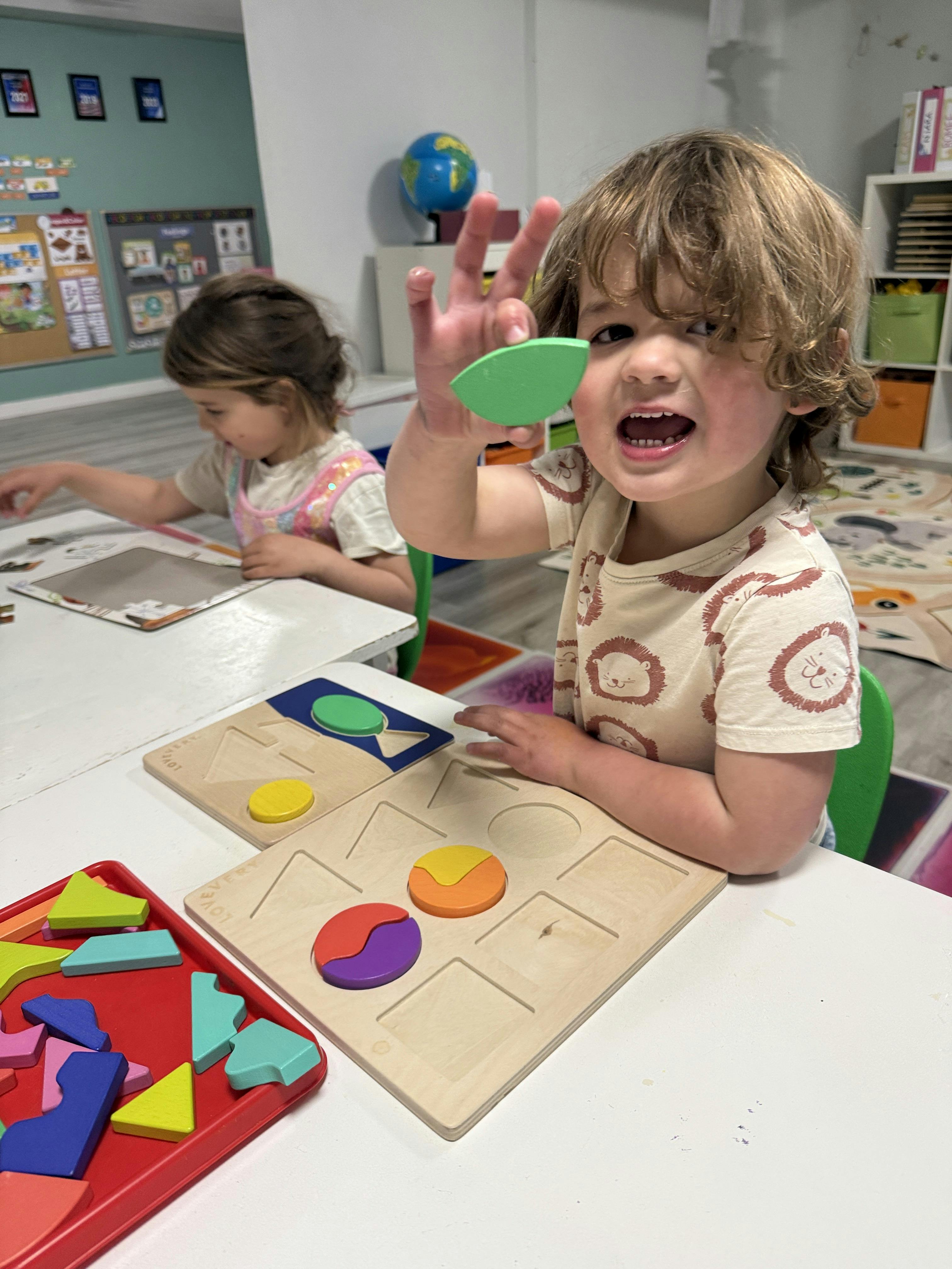 Child holding a wooden puzzle piece at a table