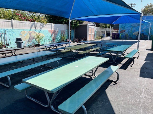 Picnic tables under blue shade canopies