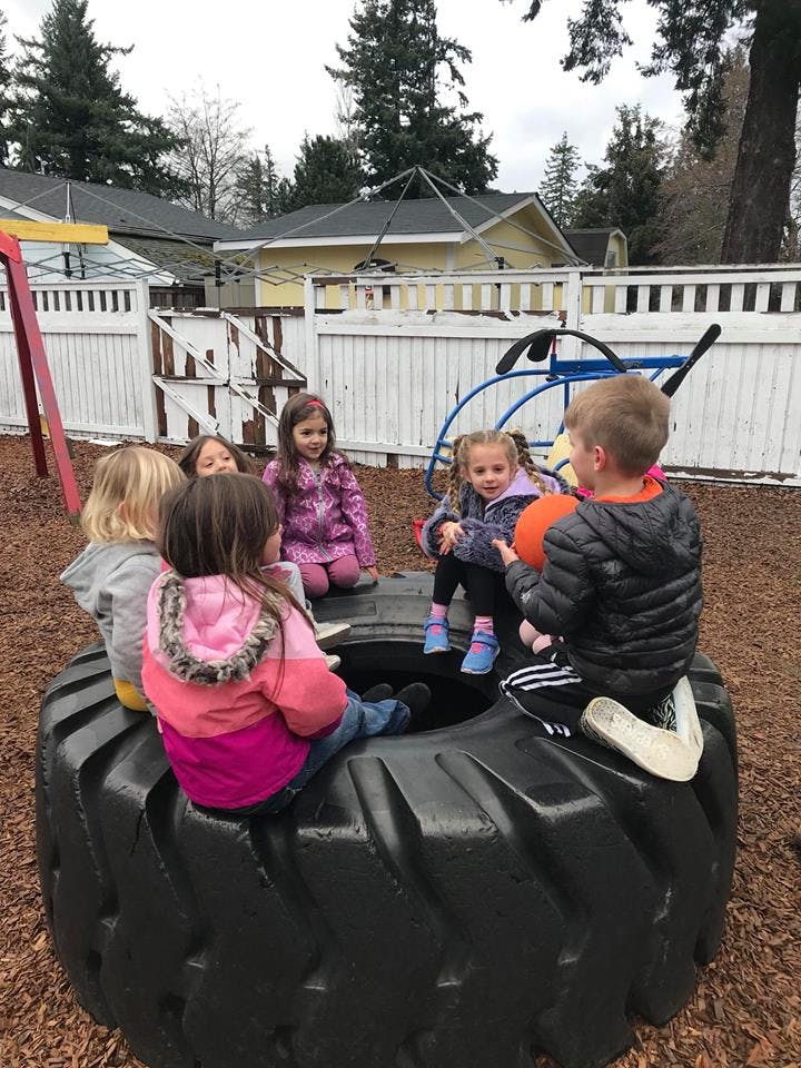 Children sitting on a large tire on a playground