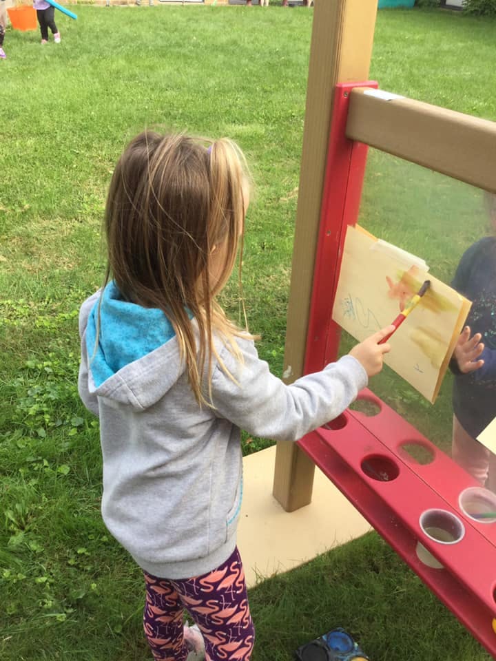Child painting on an easel outdoors