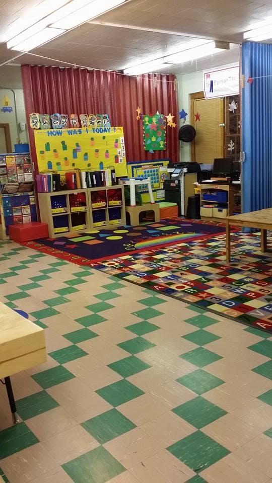 Classroom with a colorful rug, shelves, and a "How Was I Today" chart