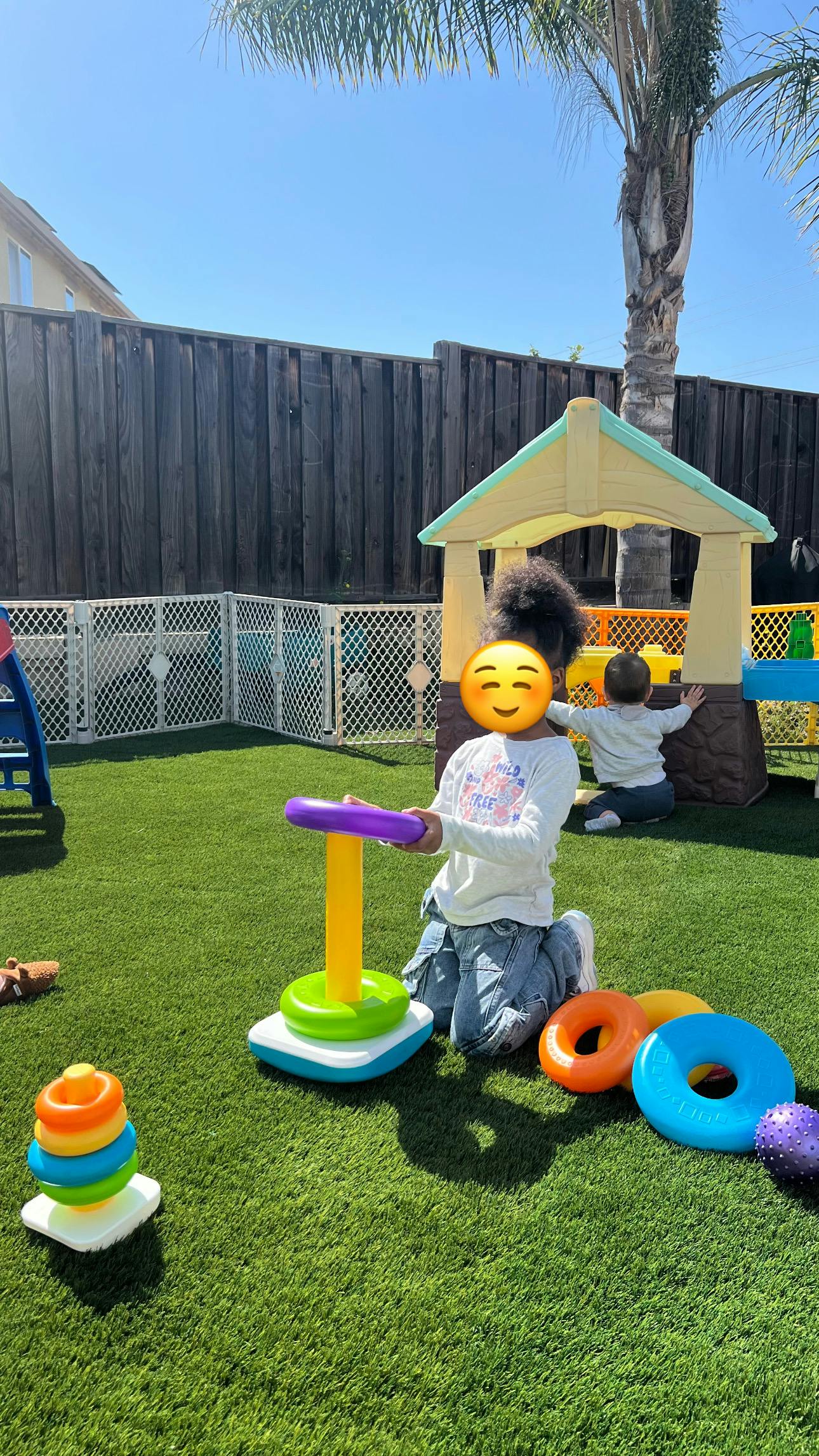 Child playing with a ring stacker toy on artificial grass