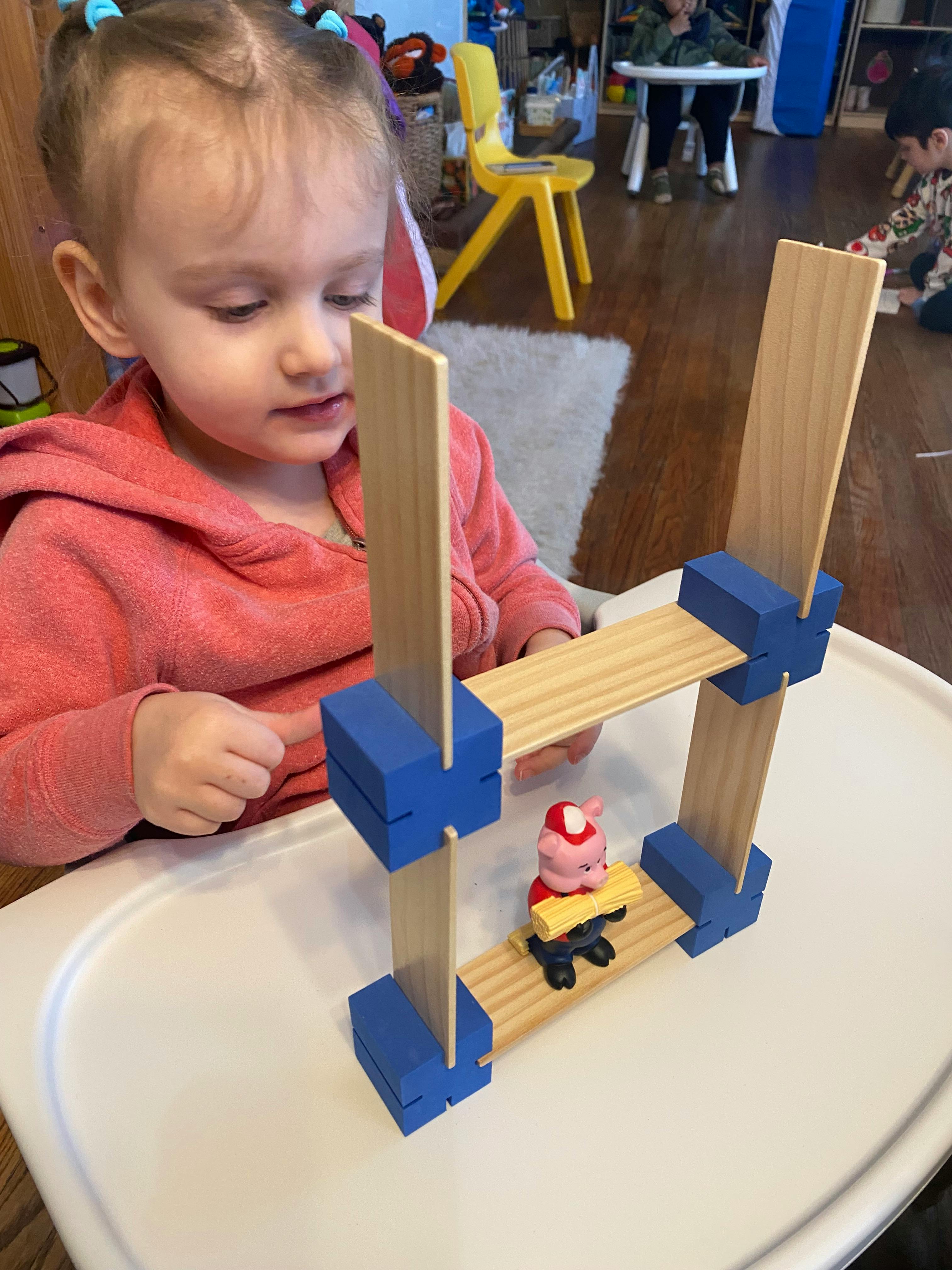 Child looking at a toy structure with a small figure