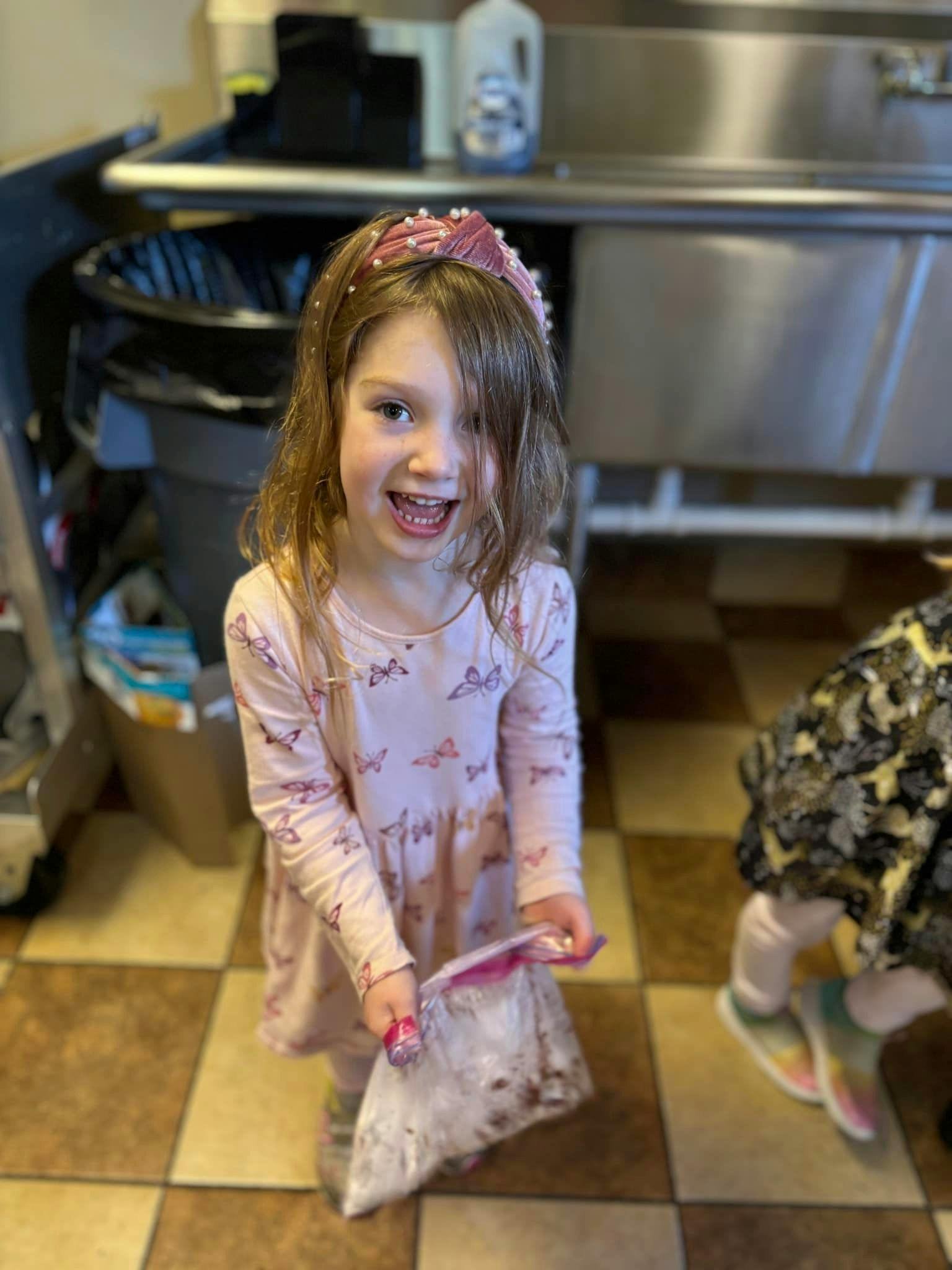 Child holding a plastic bag with contents