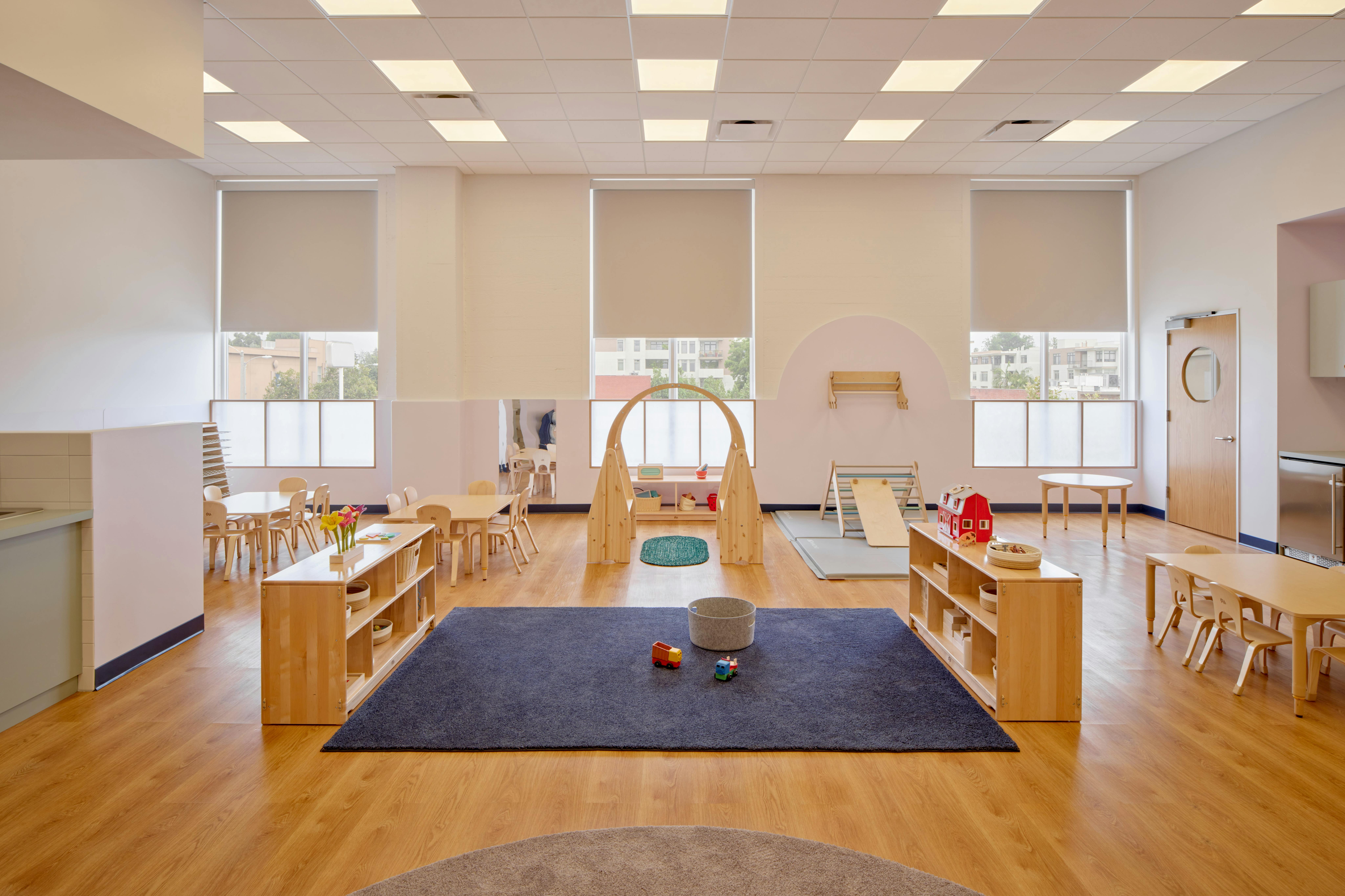 Empty classroom with small tables, chairs, and play equipment