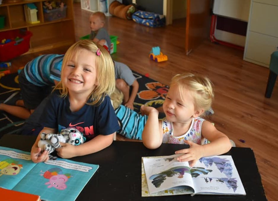 Two children looking at books at a table