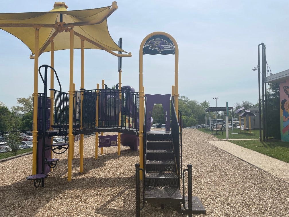 Playground structure with yellow poles and purple slides on wood chip ground