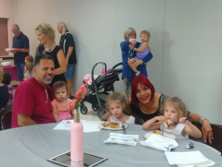 People and children sitting at a table with food