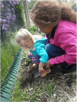 Person and child digging in dirt with a trowel