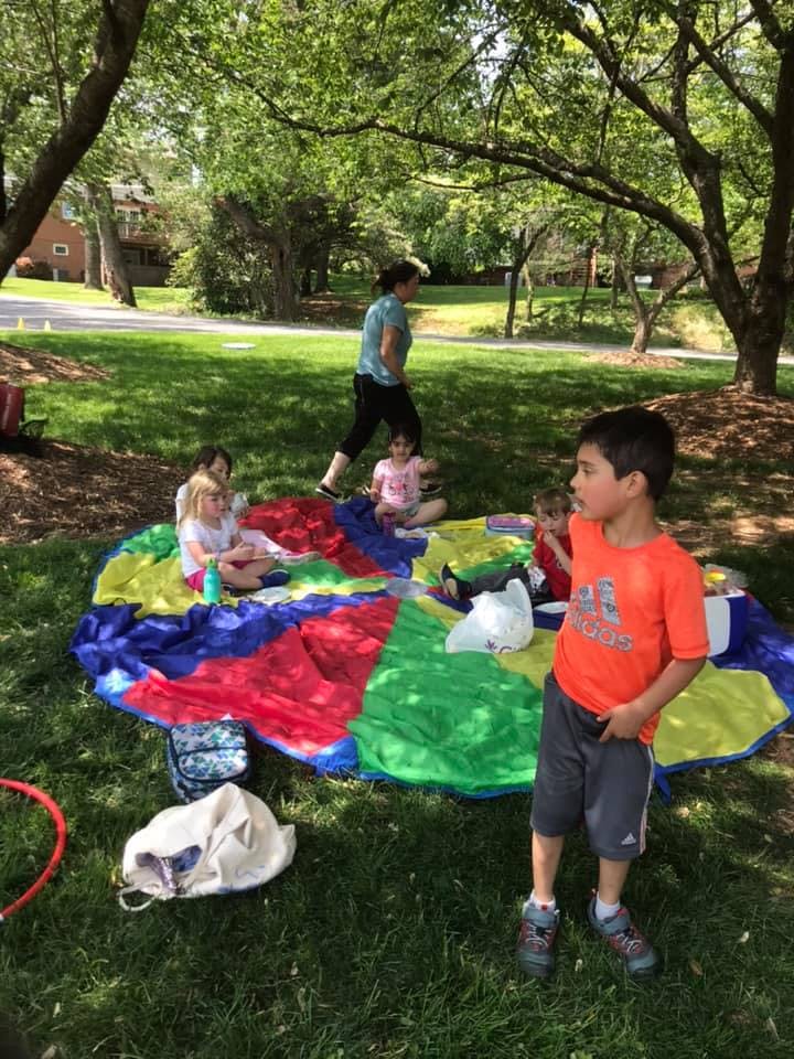 Children and an adult on a colorful parachute on grass