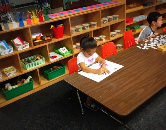 Child drawing at a table in a classroom