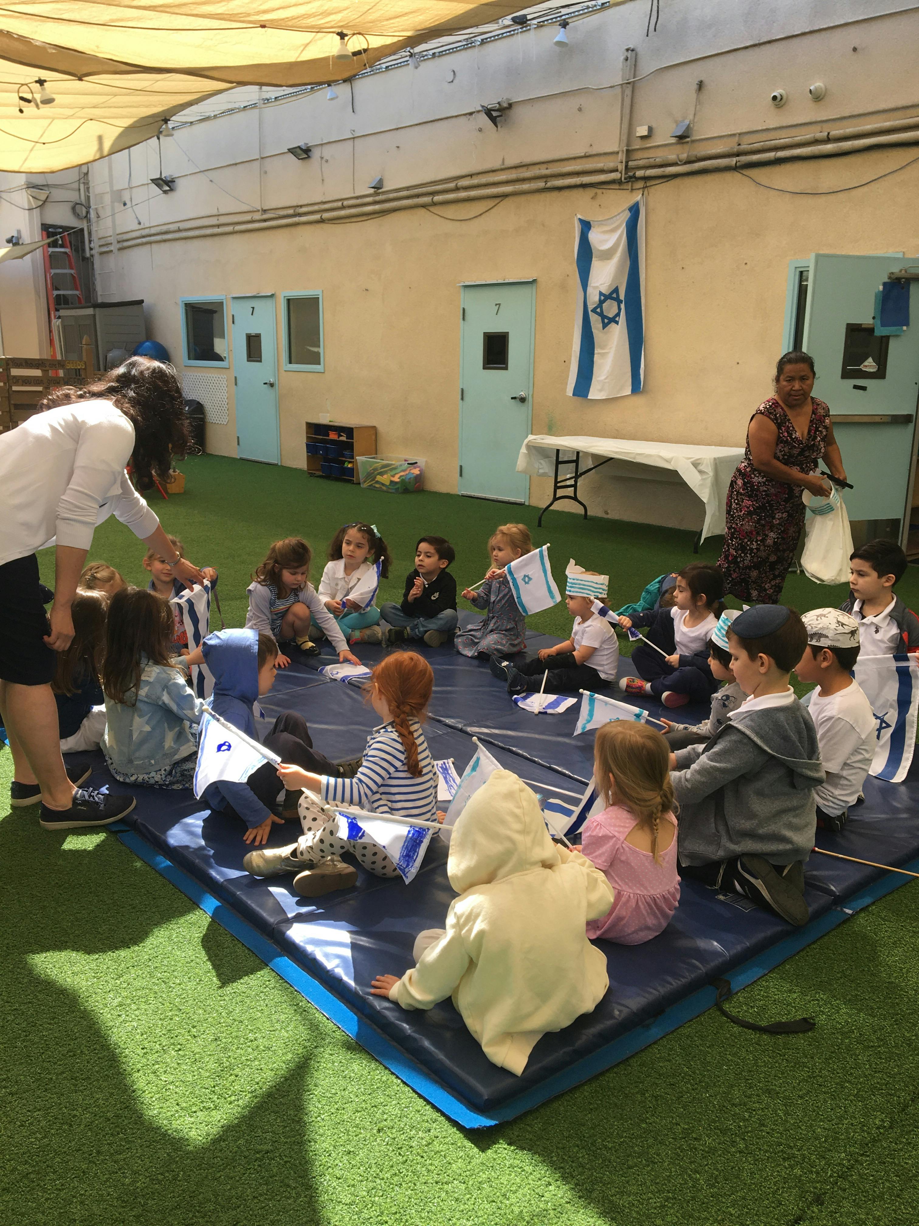 Adults and children sitting on a mat with small flags