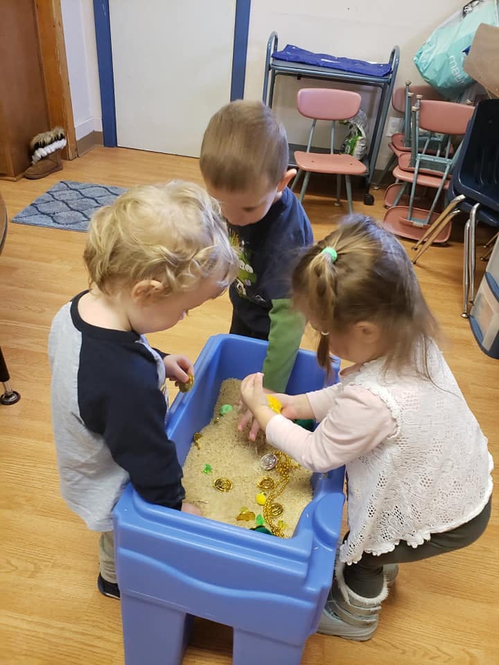 Three children playing in a sand table