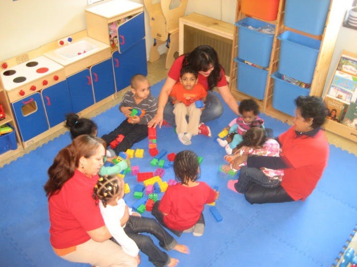 Adults and children playing with colorful blocks on a blue mat