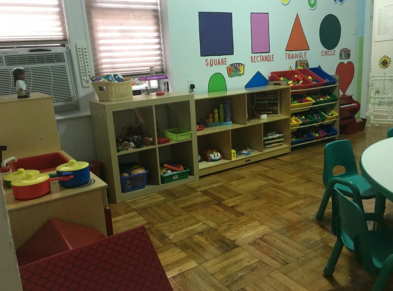 Playroom with shelves of toys, a play kitchen, and a wall with shape cutouts