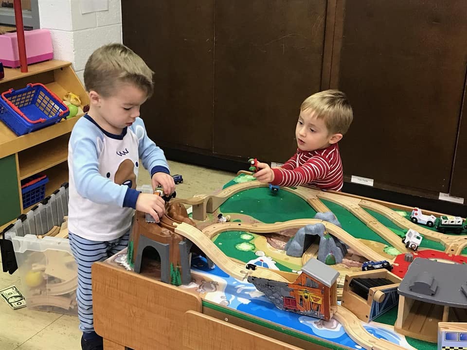 Two children playing with a toy train set