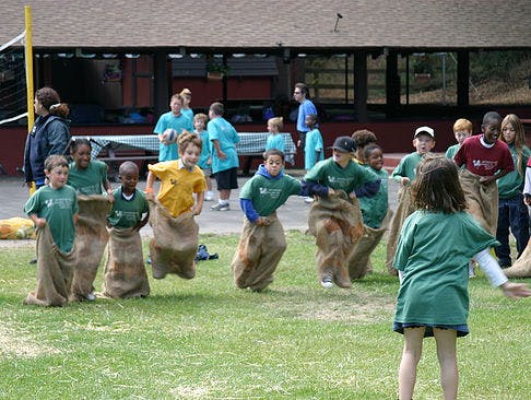 Children participating in a sack race on a grassy field
