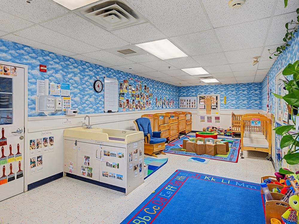daycare classroom with multiple cribs, changing station, and play area
