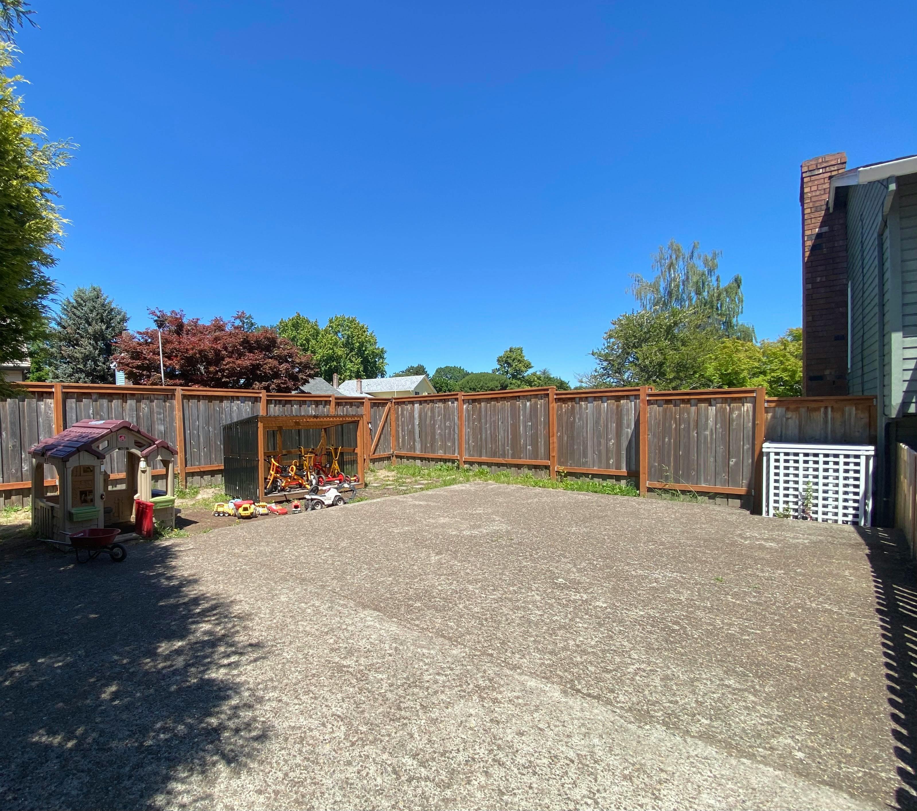 Backyard with a wooden fence, playhouse, and concrete ground