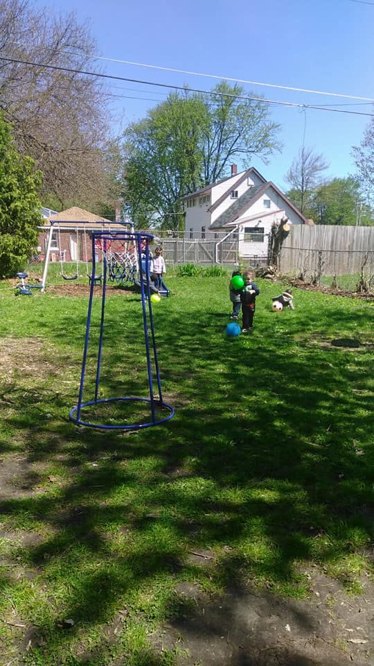 Children playing with balls in a grassy backyard