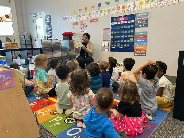 Person reading a book to a group of children in a classroom
