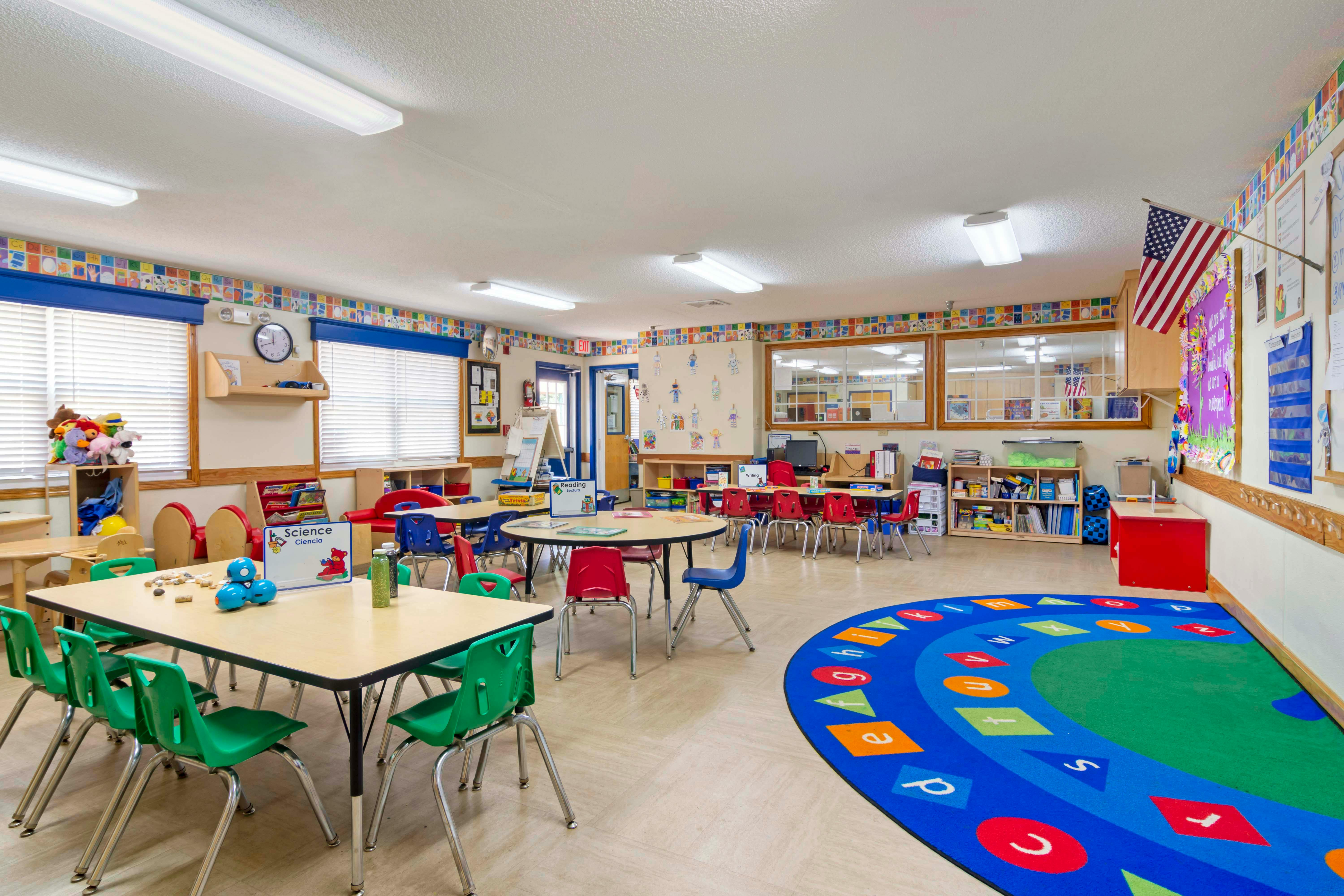 An empty elementary classroom with small tables and chairs