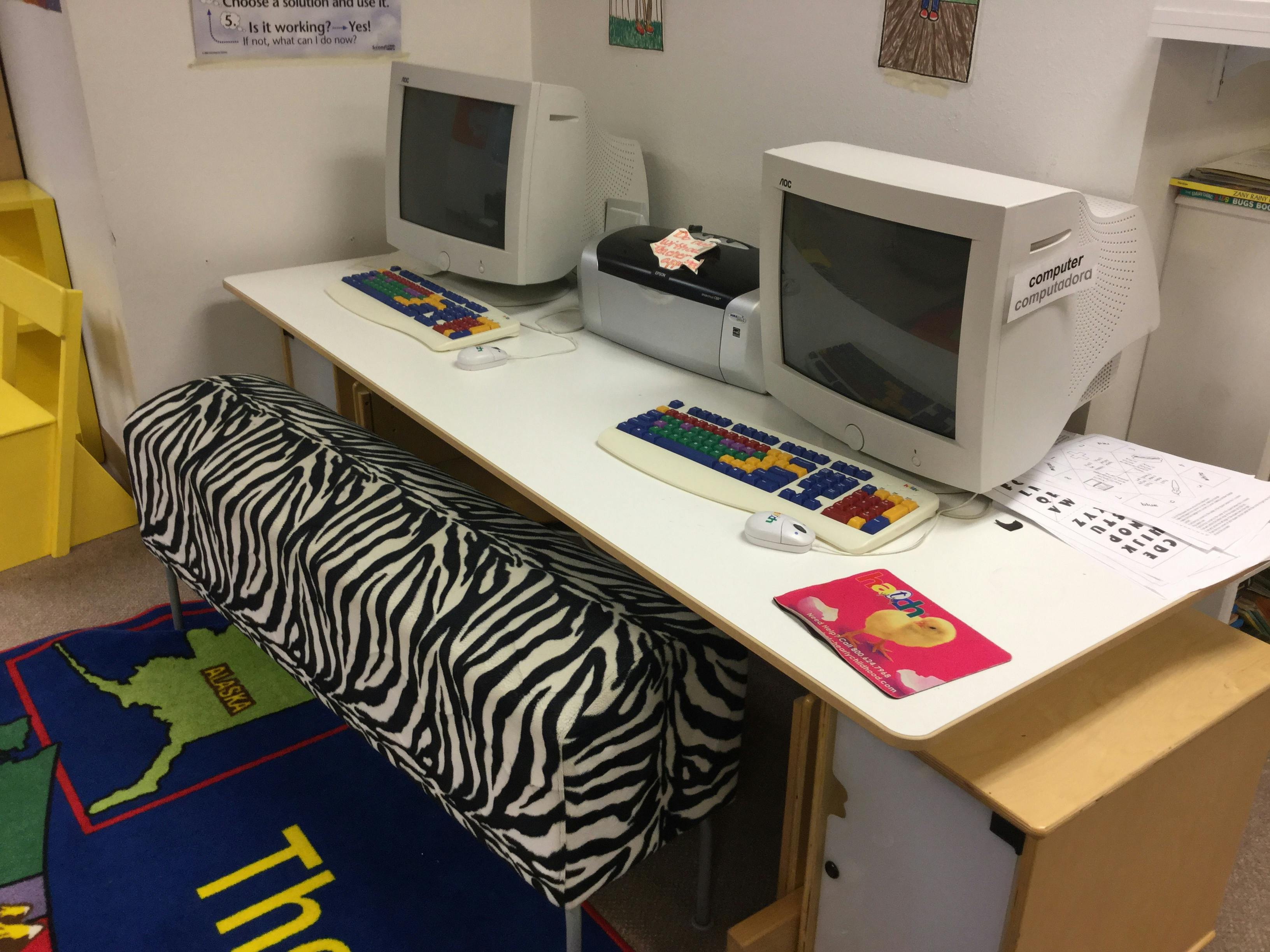 Two desktop computers with colorful keyboards on a white desk