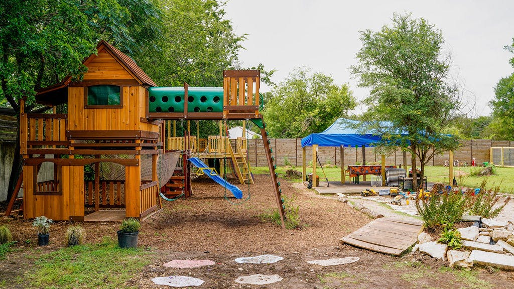 Wooden playground structure with a slide and tunnel in a backyard