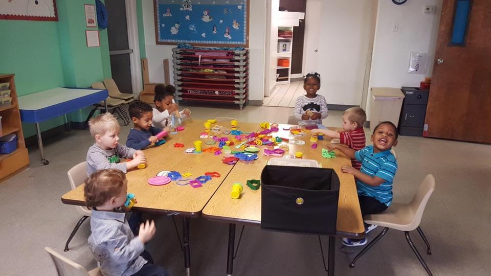 Children playing with colorful toys at a table in a classroom