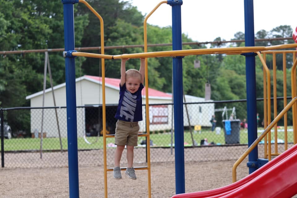 Child hanging from monkey bars on a playground