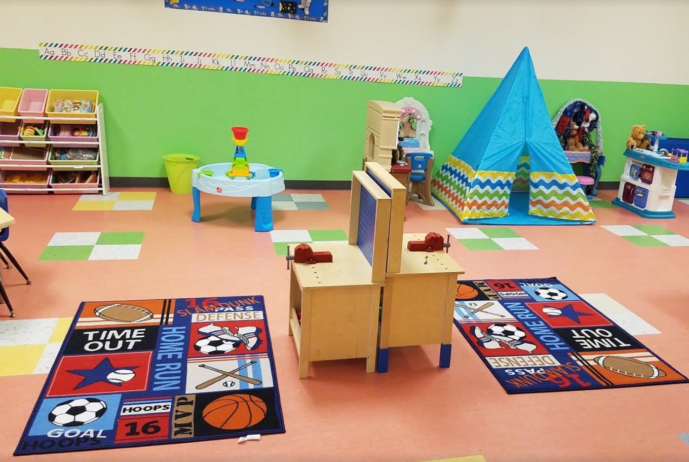 Playroom with a blue tent, play table, and two sports-themed rugs